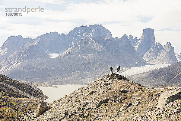 Zwei Wanderer stehen auf einem hohen Bergkamm am Akshayak Pass auf Baffin Island