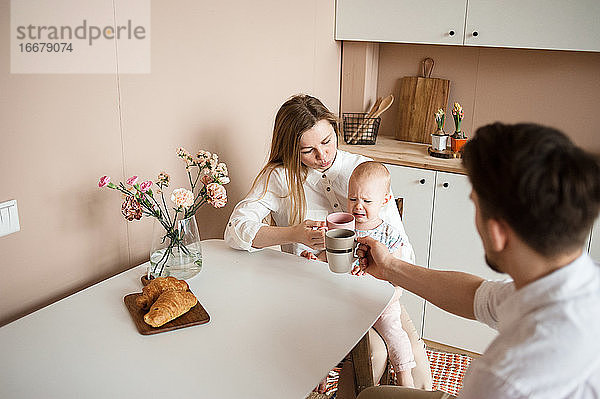 Eltern trösten ein weinendes Kind in der modernen Küche. Familienroutinen