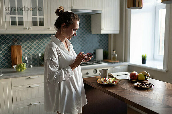 Geschäftsfrau  die beim Frühstück auf ihrem Smartphone surft