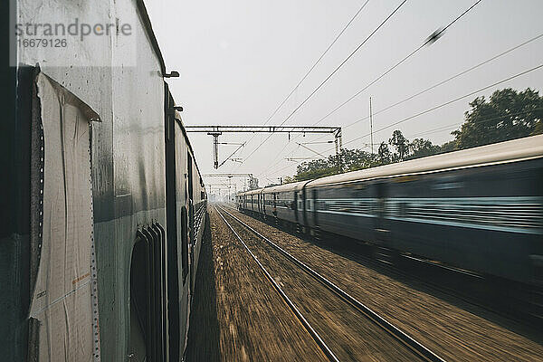 Ein gewöhnlicher Schnellzug auf der Fahrt von Neu-Delhi nach Agra überholt gerade einen anderen Zug in der Gegenrichtung.