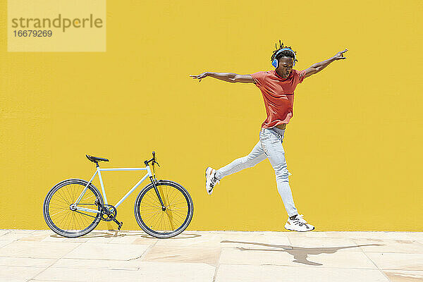 Energetischer ethnischer Mann springt in der Nähe von Fahrrad
