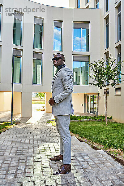 Afroamerikanischer Geschäftsmann zwischen Gebäuden  mit der Sonne im Rücken