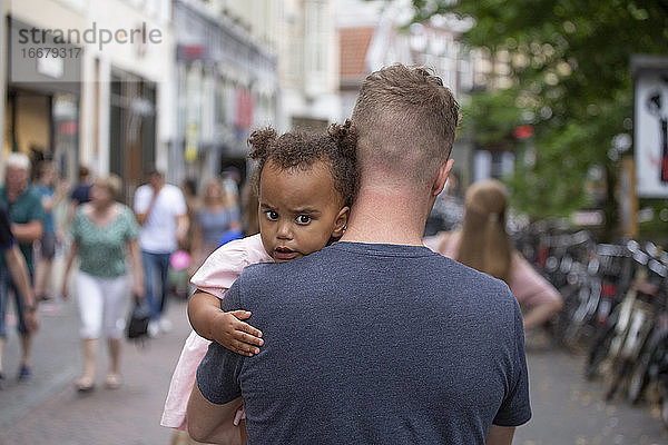 Ein Vater trägt seine kleine Tochter durch die Straßen von Europa