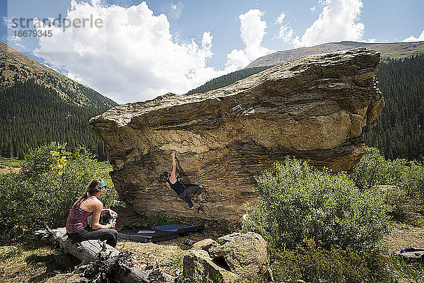 Frau schaut auf Freundin beim Bouldern am Fels