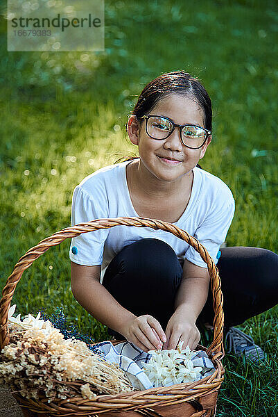 Porträt eines Mädchens  das im Park Blumen pflückt
