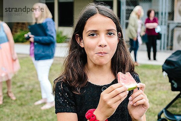 Mädchen schaut in die Kamera  nachdem sie in eine Wassermelone gebissen hat