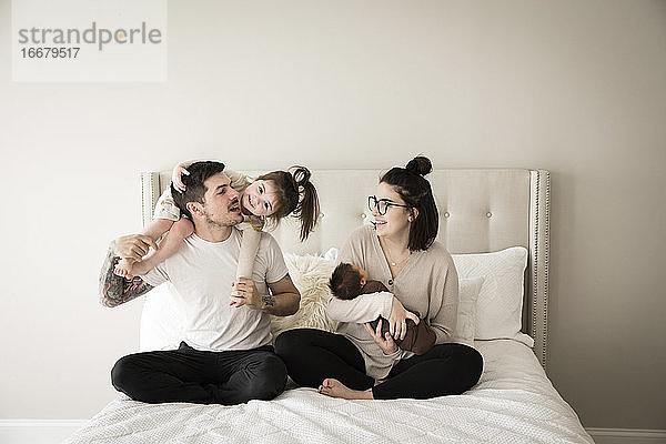 Glückliche Millennial-Familie spielt gemeinsam im Bett