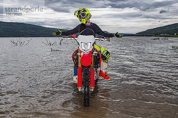 Frau posiert auf ihrem Dirt-Bike in einem See bei Pak Chong / Thailand