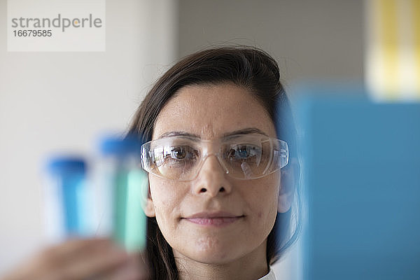 Wissenschaftlerin mit Laborbrille und Probe in einem Labor