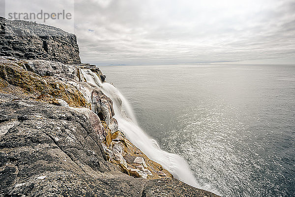 Erstaunlicher Wasserfall auf einer Klippe am Meer