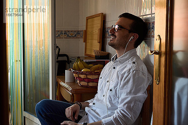 Ein junger Mann hört mit seinen Kopfhörern Musik  während er zu Hause sitzt