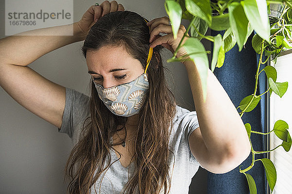 Frau zu Hause mit selbstgebauter Gesichtsmaske Schutz PSA