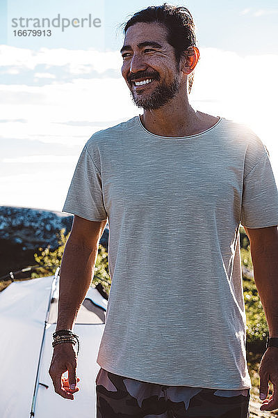 Lächelnder Mann auf einem von der Sonne beleuchteten Campingplatz