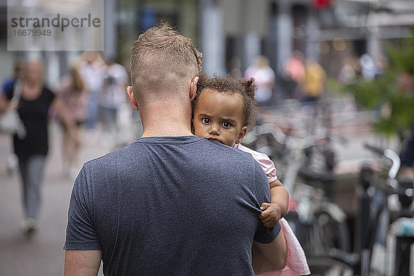 Ein junger Vater mit seiner gemischtrassigen Tochter in der Stadt