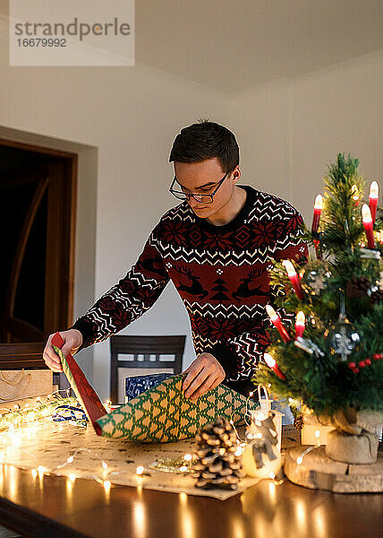 junger Mann packt Weihnachtsgeschenke für Freunde und Familie ein
