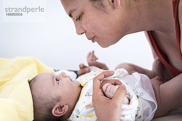 Liebevolle Mutter schaut ihr Baby an und hält seine Hände