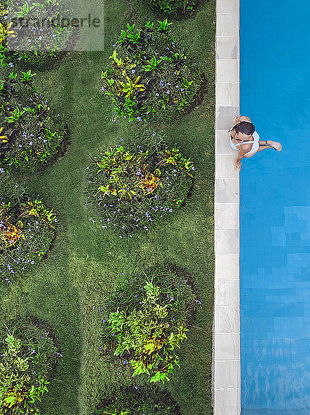 Luftaufnahme einer attraktiven Frau  die am Urlaubsort über dem Wasser schwebt