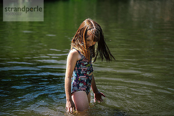 Porträt eines jungen glücklichen Mädchens  das an einem sonnigen Tag in einem Fluss spielt