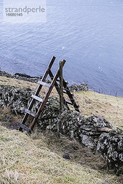 Treppe  Mauer und Zaun in voller Länge mit Fjord im Hintergrund  Färöer
