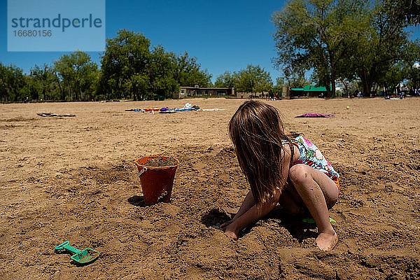 Junges Mädchen spielt im Sand an einem sonnigen Tag