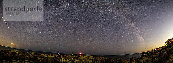 Milkyway-Panorama entlang der felsigen Küste mit Leuchttürmen darunter.