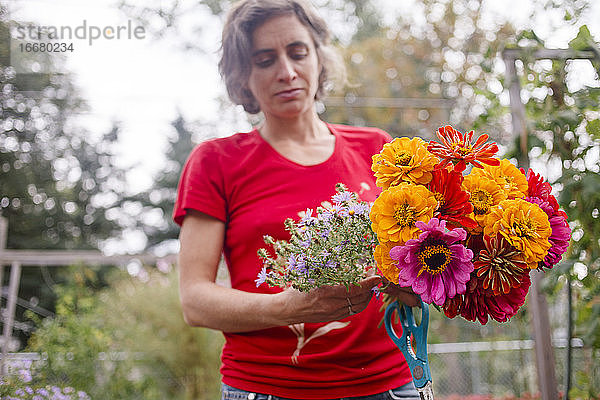 eine Gärtnerin hält einen bunten Strauß Wildblumen in die Höhe