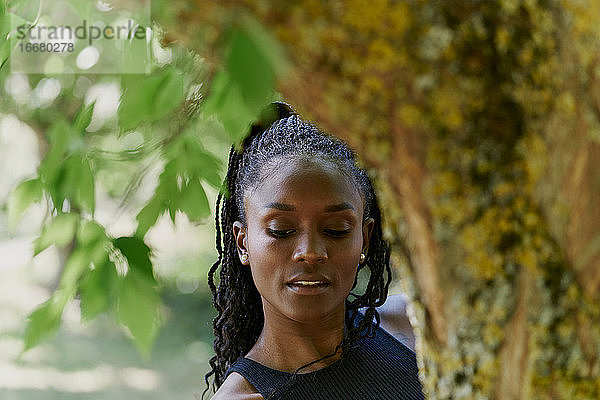 Porträt einer schönen schwarzen Frau hinter einem Baum