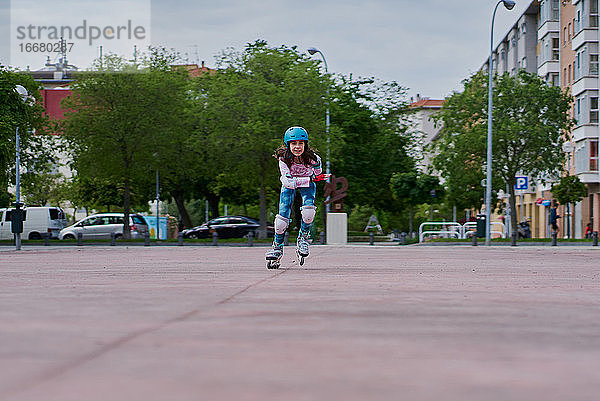 Mädchen auf der Straße skatet mit Inline-Skates und Helm