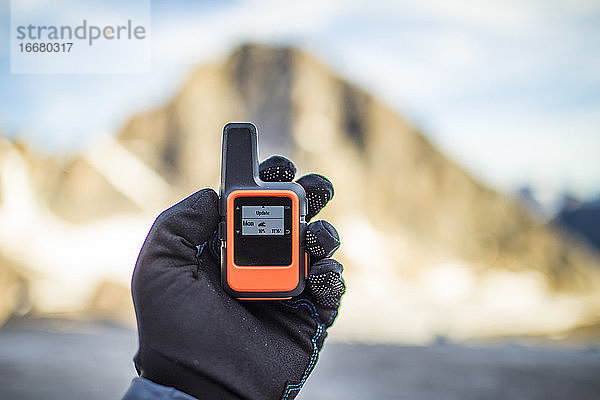 Bergsteiger prüft das Wetter über ein kleines Satellitenkommunikationsgerät.