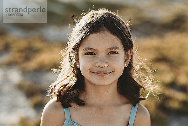 Lächelndes 8-jähriges Mädchen mit Sonnenlicht  das durch ihr dunkles Haar spielt