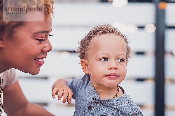 Die Mutter schaut und lächelt ihr Baby an und das Baby schaut weg