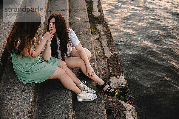 Nettes lesbisches Paar im Gespräch auf den Stufen am Fluss in der Stadt