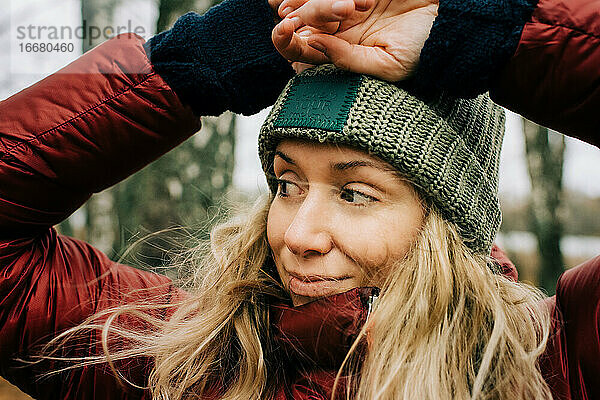 Porträt einer lächelnden Frau  die im windigen Wald in Schweden steht