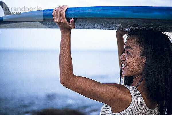 Black Multiracial Frau Lebensstil Porträt durch den Ozean mit Surfbrett