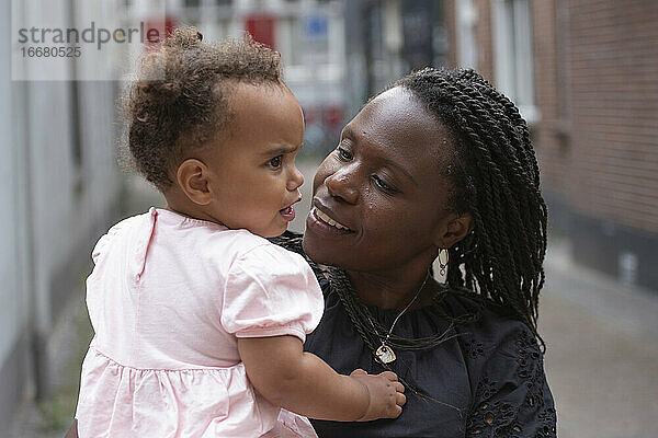 Eine schwarze Mutter versucht  ihre aufgeregte kleine Tochter zu beruhigen