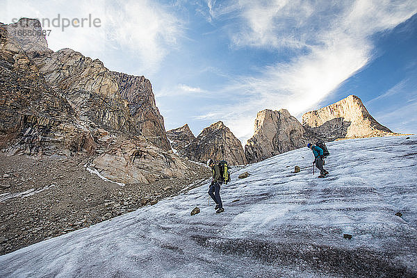 Zwei Bergsteiger überqueren einen Gletscher unterhalb des Berges Asgard.