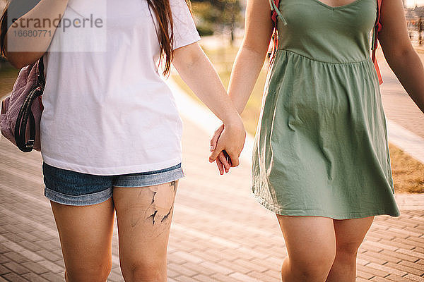 Mittelteil eines lesbischen Paares  das sich beim Spaziergang in der Stadt an den Händen hält