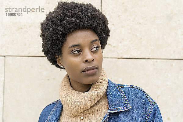 Porträt einer eleganten afrikanischen Frau mit Afro-Haar und blauer Windjacke