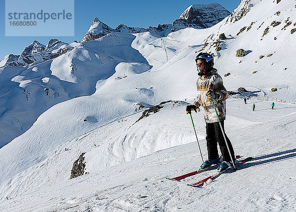 ein Junge beim Skifahren auf dem weißen Schnee von Formigal mit den Pyrenäen im Hintergrund. Horizontales Foto