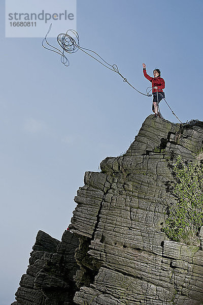 Frau wirft Seil an Windgather-Felsen im britischen Peak District