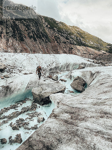 Zwei Bergsteiger beim Überqueren eines Schmelzwasserflusses auf einem Gletscher