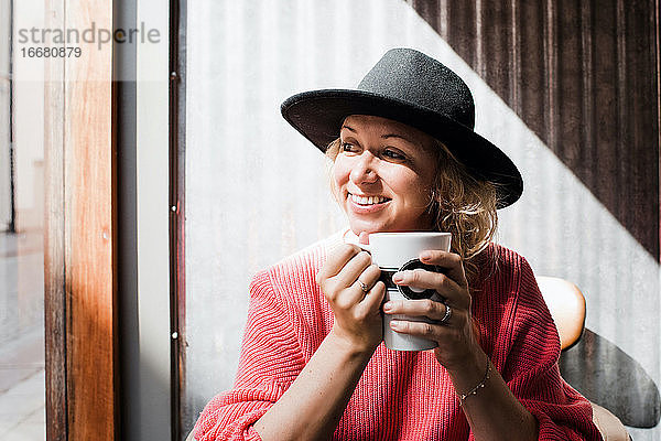 Porträt einer lächelnden Frau beim Kaffeetrinken in einem Café