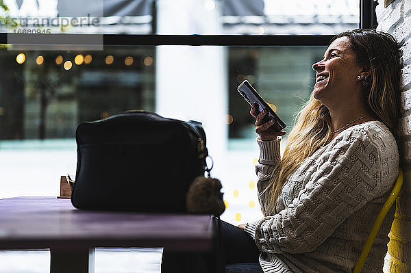 Lächelnde Frau in einem Café  die mit ihrem Mobiltelefon spricht