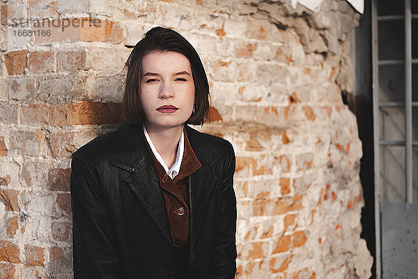 Junge Frau in Lederjacke  unauffälliges Porträt  Grunge-Hintergrund