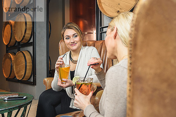 Glückliche Frauen  die Cocktails trinken und sich unterhalten