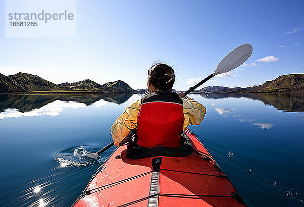 Frau rudert Seekajak auf einem stillen See in Zentralisland