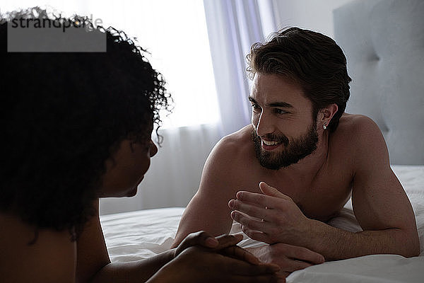 Mann spricht mit schwarzer Freundin auf dem Bett