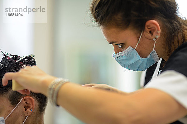 Weibliche Friseurin bei der Arbeit Schneiden färben und Styling jungen Kunden