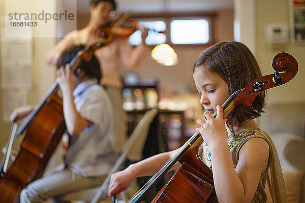 Ein kleines Kind spielt mit seiner Familie im Wohnzimmer ein Cellokonzert