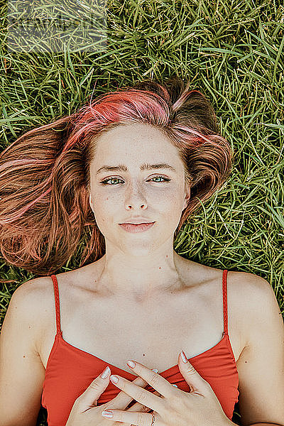Porträt einer jungen Frau  die im Freien im Gras liegt.